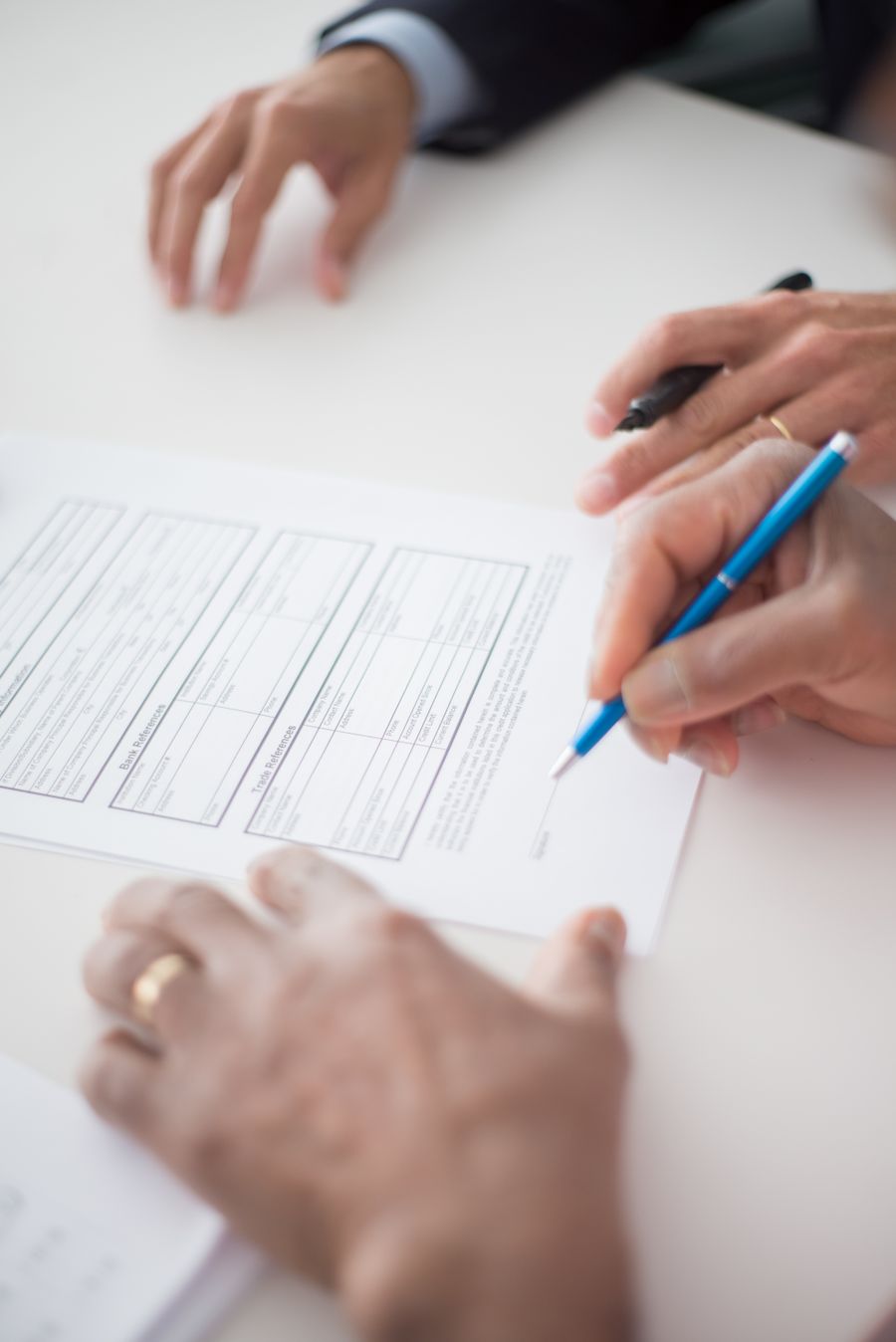 Mans signant un document laboral damunt una taula blanca. Fotografia de Kampus Production (Pexels).